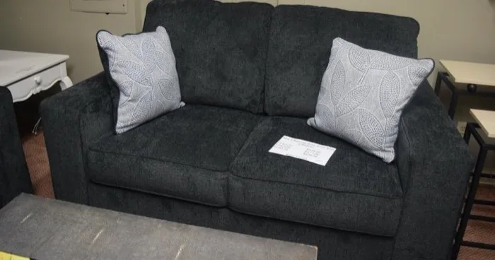 Charcoal gray loveseat with pillows at Elite Repeat Furniture Consignment